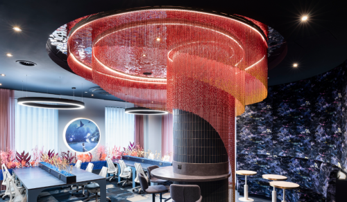 A pink and aprcioty metal chain drapery feature around a blue titled wall column in the middle of a coworking space